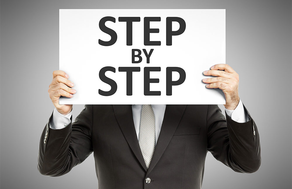 Man in suit holding a sign that says Step by Step