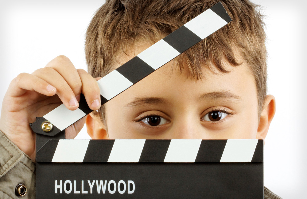 Cute child stands behind a movie slate