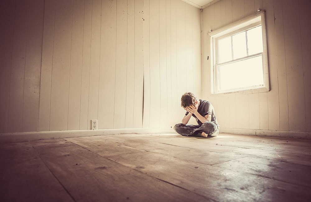 A child sits alone looking depressed