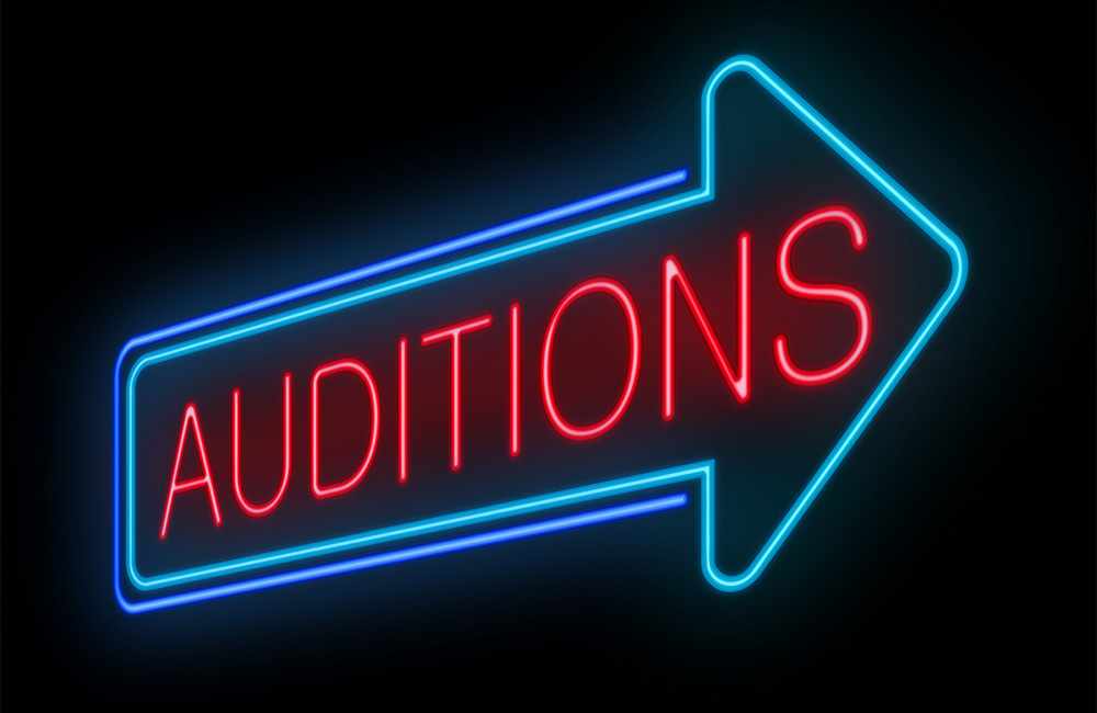 A neon arrow sign points toward auditions