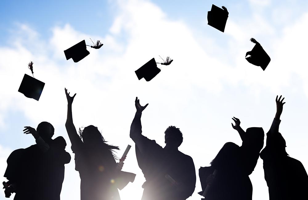 Graduating students celebrate by throwing their caps into the air