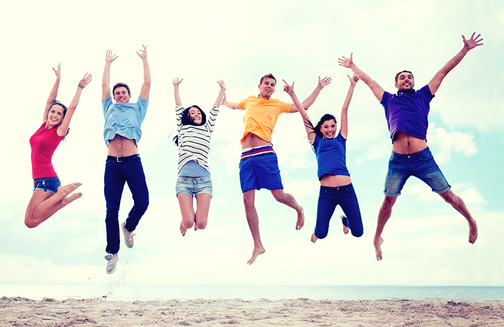 Young adults jumping and celebrating on a beach