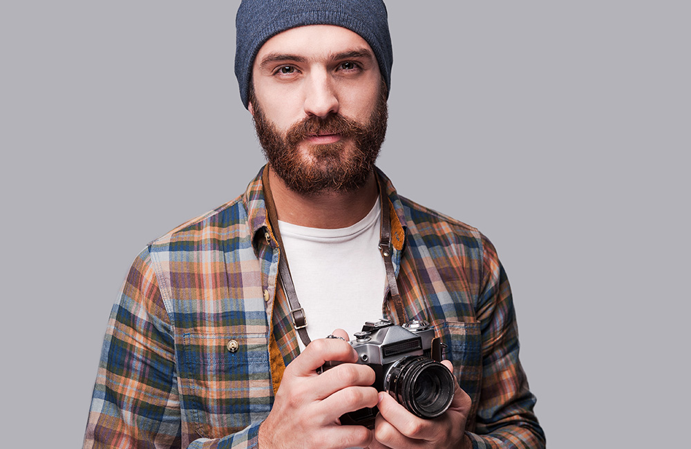 A hipster photographer holds a camera